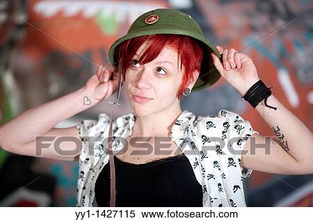 Stock Photography - A young woman with cap posing in front of a graffity.. Fotosearch