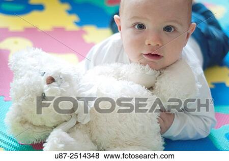 Baby Boy Holding a Teddy Bear while Looking at the Camera.. View Large Photo Image Stock Photo - Baby Boy Holding a Teddy Bear while Looking at the Camera... Fotosearch