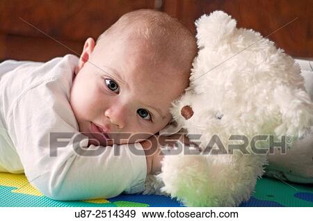 Stock Photo - Baby Boy Holding a Teddy Bear while Looking at the Camera... Fotosearch