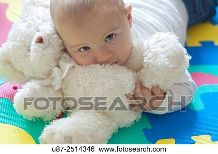 Stock Photograph - Baby Boy Holding a Teddy Bear while Looking at the Camera... Fotosearch