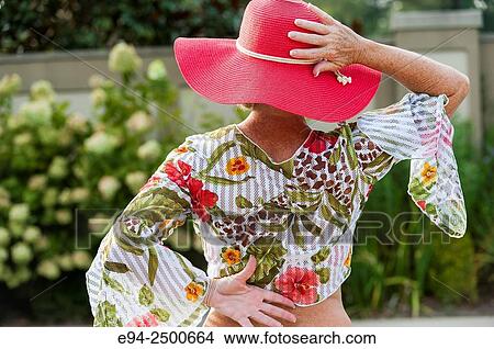 Back view of a 56 year old blond woman wearing a red hat and a casual summer top. View Large Photo Image Picture - Back view of a 56 year old blond woman wearing a red hat and a casual summer top.. Fotosearch