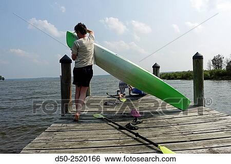 Stock Photograph - BROOMES ISLAND MARYLAND Kayaking, seaweed and mud facial, young girls looks through planks on dock.. Fotosearch