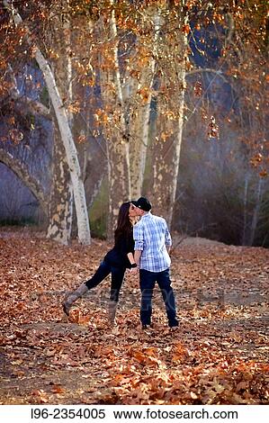 Couple walking away in a forest, playfully kissing View Large Photo Image Stock Photography - Couple walking away in a forest, playfully kissing. Fotosearch