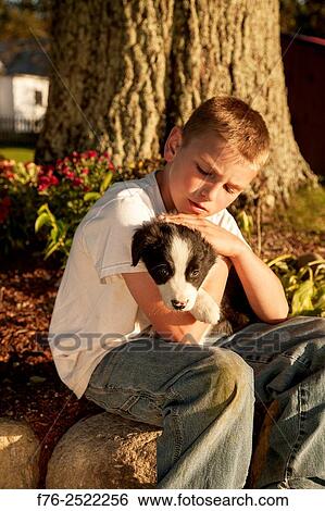 Stock Photograph - Eight year old boy cuddling, loving holding his young border collie mixed breed puppy dog. MR# 120818_2... Fotosearch