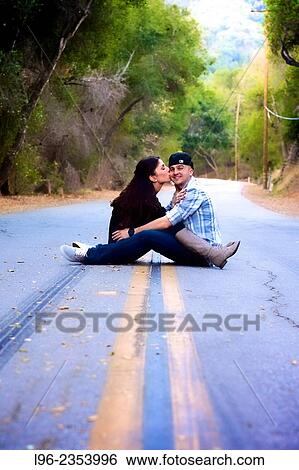 Engaged couple sitting together on a scenic road, kissing View Large Photo Image Stock Photograph - Engaged couple sitting together on a scenic road, kissing. Fotosearch