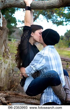 Engaged, playful, happy couple, embracing and kissing in a tree View Large Photo Image Stock Image - Engaged, playful, happy couple, embracing and kissing in a tree. Fotosearch