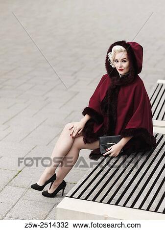 Fashionable blond wearing red coat and she sits on a city bench, urban scene. View Large Photo Image Stock Image - Fashionable blond wearing red coat and she sits on a city bench, urban scene.. Fotosearch