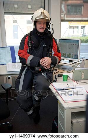 Picture - Firefighter in fireproof turnout gear on his regular job in the barracks.. Fotosearch