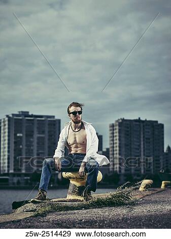 Handsome man wearing white shirt and jeans, windy day in harbour. View Large Photo Image Stock Photo - Handsome man wearing white shirt and jeans, windy day in harbour.. Fotosearch