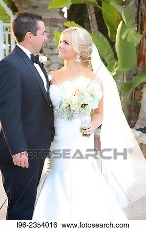 Stock Photograph - Happy married couple embracing after their garden wedding. Fotosearch