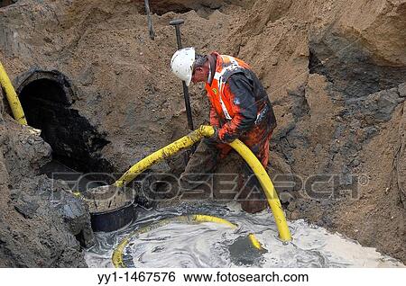 Stock Photograph - Man repairing old sewer pipe and replacing it for another one.. Fotosearch