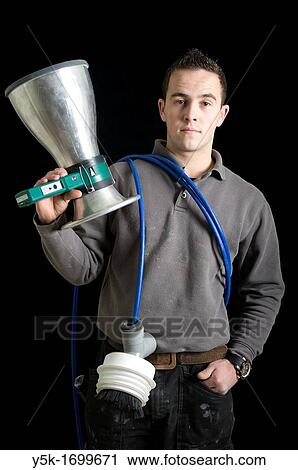Stock Image - Portrait of a ventilation specialist, with his tools, before a black background. Photograph - portrait taken during the reconstruction of a bathroom.. Fotosearch