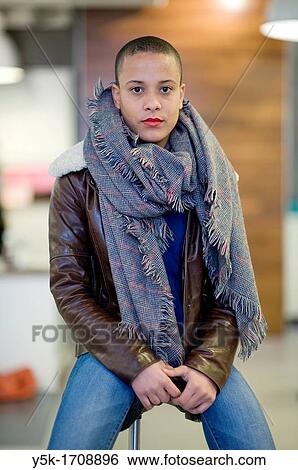 Stock Photograph - Portrait of a young, African woman, while sitting on a stool in a hair-salon.. Fotosearch