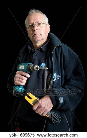 Stock Photography - Portrait of an electrician, with his drill and other tools, in front of a black background. Photograph - portrait taken during the reconstruction of a bathroom.. Fotosearch