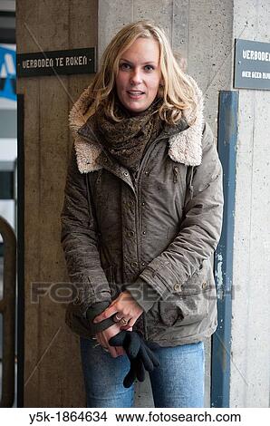 Rotterdam, Netherlands. Attractive, blonde woman in winter fashion, leaning against concrete pillar of an industrial building. View Large Photo Image Picture - Rotterdam, Netherlands. Attractive, blonde woman in winter fashion, leaning against concrete pillar of an industrial building.. Fotosearch