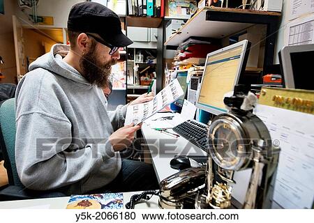 Rotterdam, Netherlands. The coordinator of an art studio and gallery down town, looking at contactsheets of images, while sitting behind his desk. View Large Photo Image Stock Image - Rotterdam, Netherlands. The coordinator of an art studio and gallery down town, looking at contactsheets of images, while sitting behind his desk.. Fotosearch