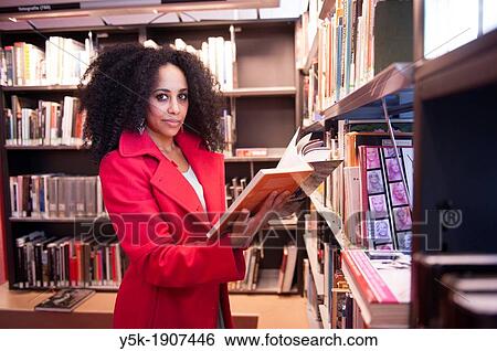Rotterdam, Netherlands. Young, African woman, searching for a suitable book, between the bookshelves in a public library. View Large Photo Image Stock Photograph - Rotterdam, Netherlands. Young, African woman, searching for a suitable book, between the bookshelves in a public library.. Fotosearch