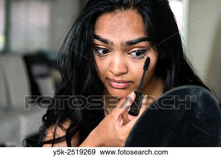 Rotterdam, Netherlands. Young, attractive Hindustani woman, at home applying makeup to her face. View Large Photo Image Stock Photo - Rotterdam, Netherlands. Young, attractive Hindustani woman, at home applying makeup to her face.. Fotosearch