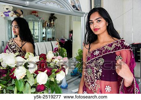 Rotterdam, Netherlands. Young, attractive Hindustani woman, wearing a traditional gown, standing in front of her living room mirror. View Large Photo Image Stock Photo - Rotterdam, Netherlands. Young, attractive Hindustani woman, wearing a traditional gown, standing in front of her living room mirror.. Fotosearch