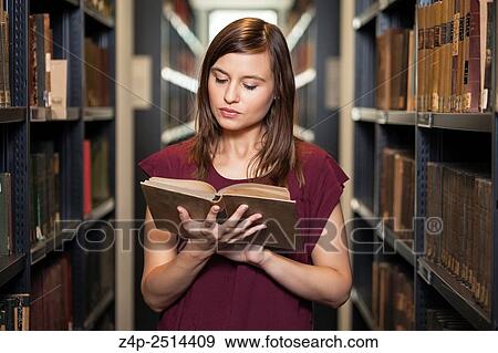 Stock Photo - Student reading a book in library. Fotosearch