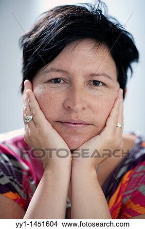 Picture - Studio portrait of en middle-aged woman, leaning on her hands.. Fotosearch