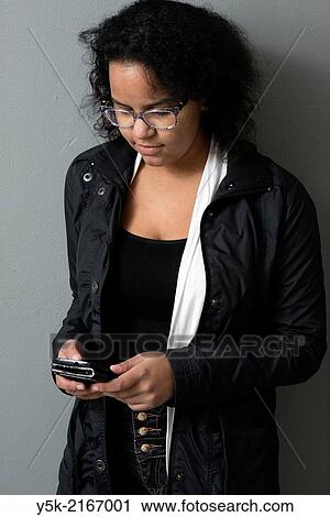 Studio Tuinstraat, Tilburg, Netherlands. Studio-portrait of a young, Caribbean woman, using her smartphone to monitor social media. View Large Photo Image Stock Image - Studio Tuinstraat, Tilburg, Netherlands. Studio-portrait of a young, Caribbean woman, using her smartphone to monitor social media.. Fotosearch