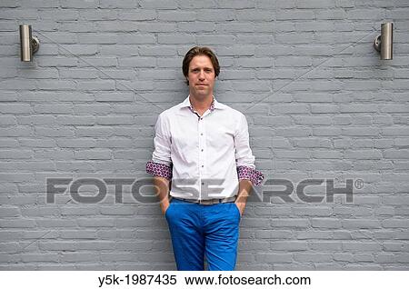 Teteringen; Netherlands. Independant accountant in white shirt; leaning against the wall in his back yard. View Large Photo Image Stock Photography - Teteringen; Netherlands. Independant accountant in white shirt; leaning against the wall in his back yard.. Fotosearch
