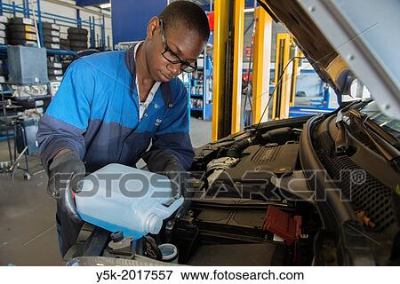 Tilburg, Netherlands. A mechanic or apprentice engineer, immigrated from the Caribbean islands to the Netherlands, in his workshop working on the regular, periodical maintenance of a car. View Large Photo Image Stock Photo - Tilburg, Netherlands. A mechanic or apprentice engineer, immigrated from the Caribbean islands to the Netherlands, in his workshop working on the regular, periodical maintenance of a car.. Fotosearch