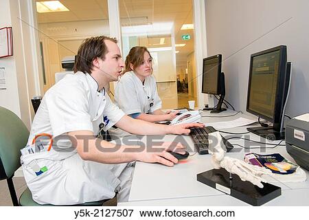 Tilburg, Netherlands. Doctor / physician on a hospitals first aid ward, with his student medicine, reviewing the data of a patient before making a diagnosis View Large Photo Image Stock Photo - Tilburg, Netherlands. Doctor / physician on a hospitals first aid ward, with his student medicine, reviewing the data of a patient before making a diagnosis. Fotosearch