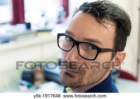 Stock Photo - Tilburg, Netherlands. Graphic disigner and art director looking back, from his work towards the camera.. Fotosearch