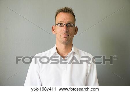 Tilburg, Netherlands. Portrait of a young man, wearing glasses, against a grey, studio background. View Large Photo Image Stock Image - Tilburg, Netherlands. Portrait of a young man, wearing glasses, against a grey, studio background.. Fotosearch
