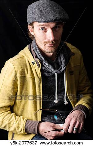 Stock Photo - Tilburg, Netherlands. Portrait of a young man with cap and glasses.. Fotosearch