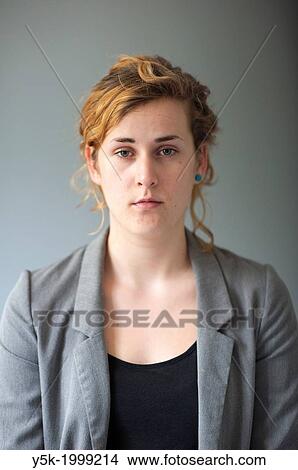 Picture - Tilburg, Netherlands. Studio-portrait of a young woman against a grey background, looking into the camera. Front view.. Fotosearch