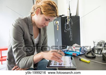 Tilburg, Netherlands. Studio-portrait of a young woman, working on her Digital Tablet, viewing images on the AGE FotoStock website, using the local WiFi network of the photographer. View Large Photo Image Stock Photograph - Tilburg, Netherlands. Studio-portrait of a young woman, working on her Digital Tablet, viewing images on the AGE FotoStock website, using the local WiFi network of the photographer.. Fotosearch