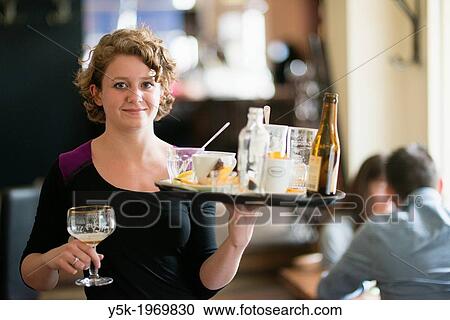 Tilburg, Netherlands. Young woman working part-time as a waitress in a cafe-restaurant, carrying tray of dirty and used glasses. View Large Photo Image Stock Image - Tilburg, Netherlands. Young woman working part-time as a waitress in a cafe-restaurant, carrying tray of dirty and used glasses.. Fotosearch