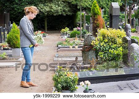 Tilburg, Netherlands. Young woman visiting the grave of a deceased person on a local cemetery. View Large Photo Image Stock Photo - Tilburg, Netherlands. Young woman visiting the grave of a deceased person on a local cemetery.. Fotosearch