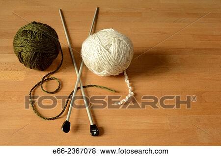 Two balls of wool (one dark green, one white) laying on table with knitting needles. View Large Photo Image Stock Photo - Two balls of wool (one dark green, one white) laying on table with knitting needles.. Fotosearch