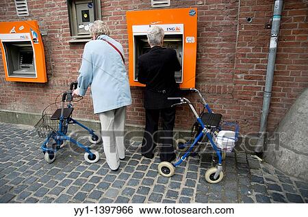 Two older women withdraw cash money from an ATM Machine. View Large Photo Image Stock Photograph - Two older women withdraw cash money from an ATM Machine.. Fotosearch