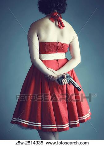 Woman hide a gun behind her back, cross-processed studio shot. View Large Photo Image Stock Photograph - Woman hide a gun behind her back, cross-processed studio shot.. Fotosearch