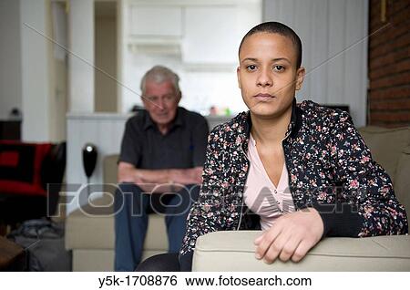 Young African woman, with her father in the background, sitting in her living-room. View Large Photo Image Stock Photograph - Young African woman, with her father in the background, sitting in her living-room.. Fotosearch
