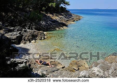 young woman lying on rocks at a creek of Mrcara islet in the north-west of Lastovo island, Croatia, Southeast Europe. View Large Photo Image Stock Photo - young woman lying on rocks at a creek of Mrcara islet in the north-west of Lastovo island, Croatia, Southeast Europe.. Fotosearch