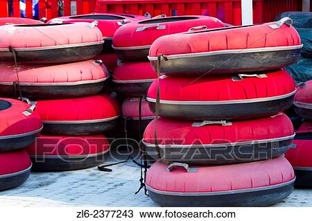 Stock Image - A bunch of sleds, and bouees stack onto each other and line up on snow ready to be used.. Fotosearch