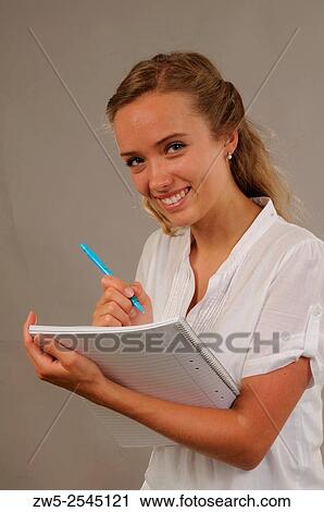 Stock Image - A businesswoman in an office holding a pen and clipboard.. Fotosearch