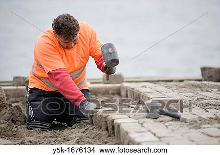 A road worker, making new pavement on one of the docks in Rotterdam harbor. View Large Photo Image Picture - A road worker, making new pavement on one of the docks in Rotterdam harbor.. Fotosearch