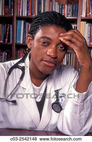 A tired African American woman physician poses in a Los Angeles medical reference library. Note stethoscope and traditional doctor´s white coat. MODEL RELEASE. View Large Photo Image Stock Photo - A tired African American woman physician poses in a Los Angeles medical reference library. Note stethoscope and traditional doctor´s white coat. MODEL RELEASE.. Fotosearch