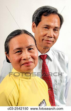 Stock Image - A Vietnamese American husband and wife pose in Westminster, CA. Note wife in traditional dress. MODEL RELEASE.. Fotosearch