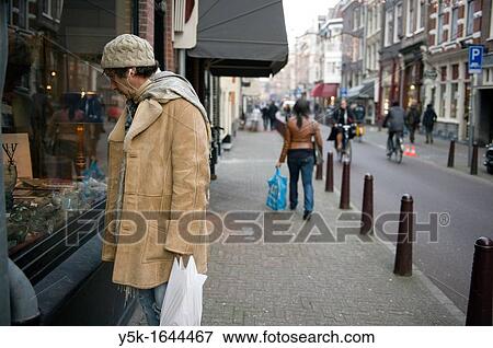 Amsterdam, Netherlands. A middle-aged man studying a store-window full of antique. View Large Photo Image Stock Photo - Amsterdam, Netherlands. A middle-aged man studying a store-window full of antique.. Fotosearch