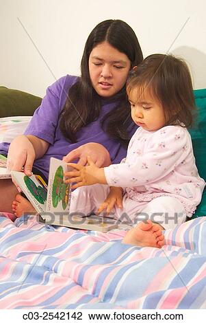 An Asian American teen girl reads to her infant sister in bed while babysitting in Laguna Beach, CA. MODEL RELEASE. View Large Photo Image Stock Image - An Asian American teen girl reads to her infant sister in bed while babysitting in Laguna Beach, CA. MODEL RELEASE.. Fotosearch