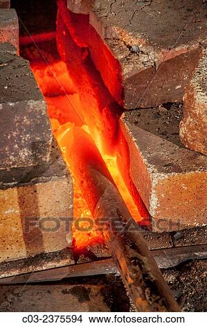 An iron bar is heated red-hot in the forge of a blacksmith's shop. Note fire bricks. View Large Photo Image Picture - An iron bar is heated red-hot in the forge of a blacksmith's shop. Note fire bricks.. Fotosearch