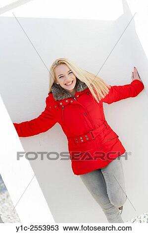 Stock Image - Blond teen girl in Red jacket spreading hands. Fotosearch